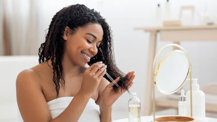 Mulher aplicando óleo hidratante nas pontas do cabelo após o banho