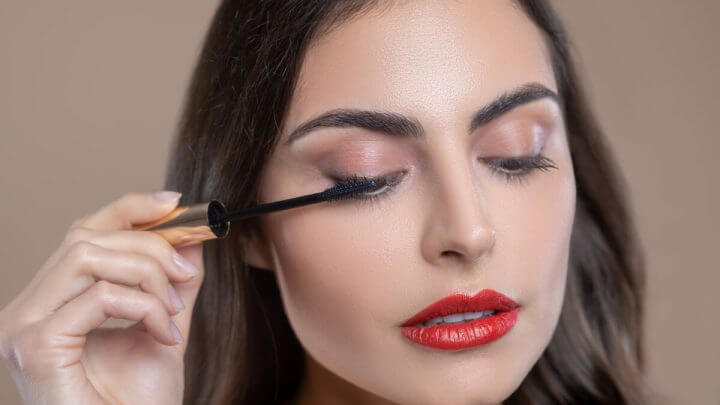Mulher passando rímel nos olhos