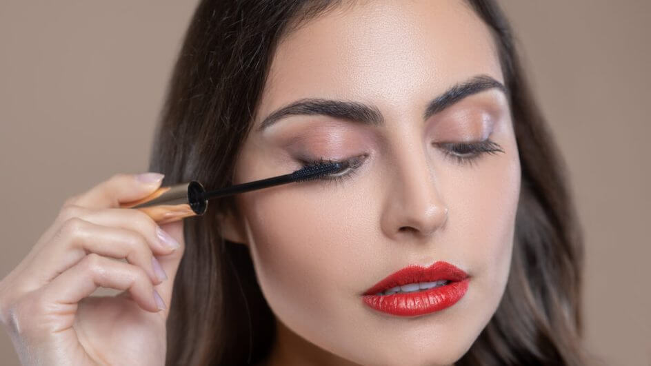 Mulher passando rímel nos olhos