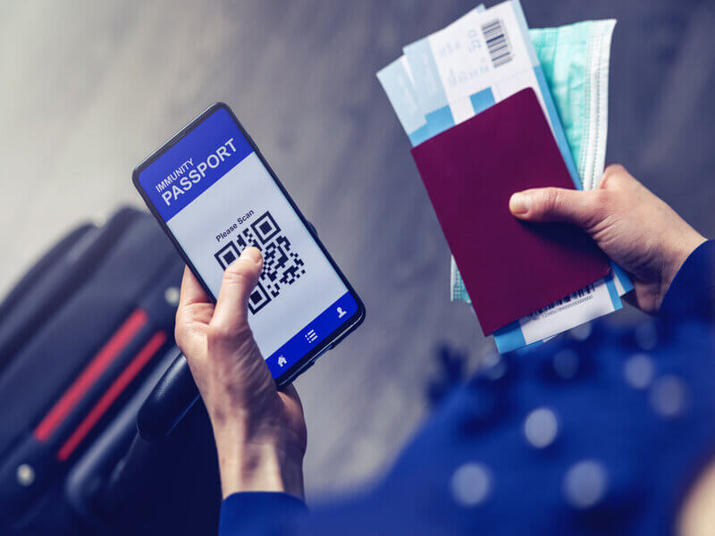 Pessoa segurando um celular com QR Code e passaporte