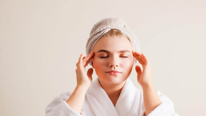 Mulher fazendo automassagem facial em casa