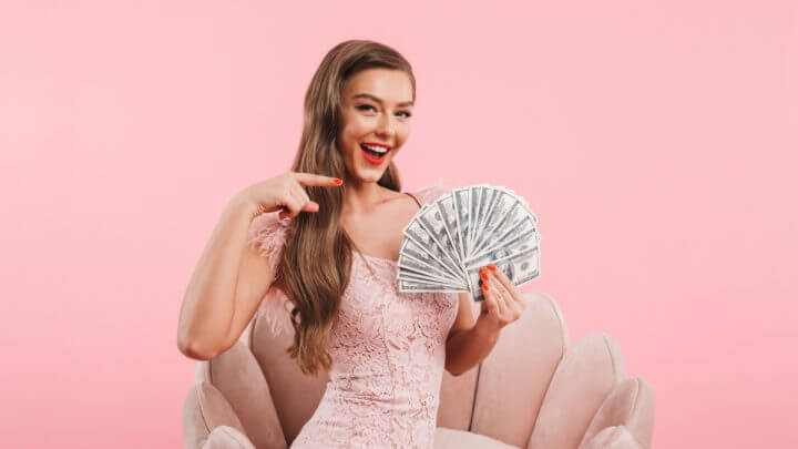 Mulher com vestido rosa segurando dinheiro