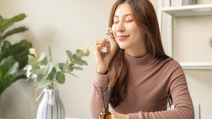 Jovem asiática segurando flor e apreciando o cheiro
