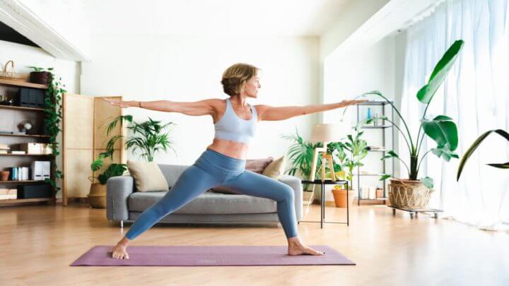 Mulher realizando yoga em um ambiente interno, bem iluminado e com plantas
