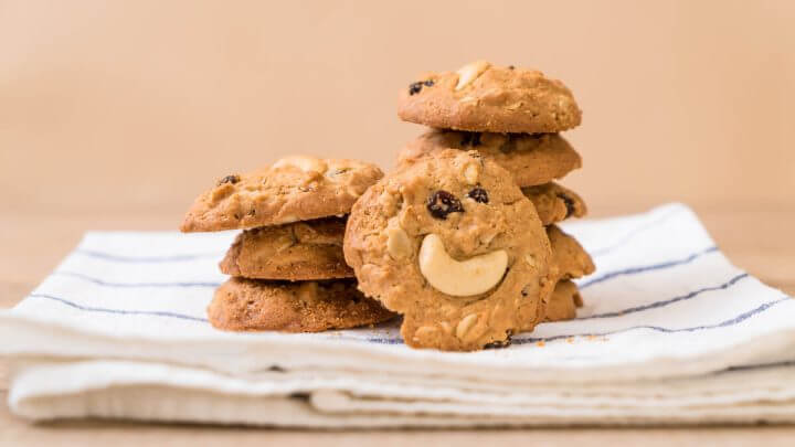 Biscoitos descorados com castanha-de-caju e uvas-passas empilhados em cima de um pano branco