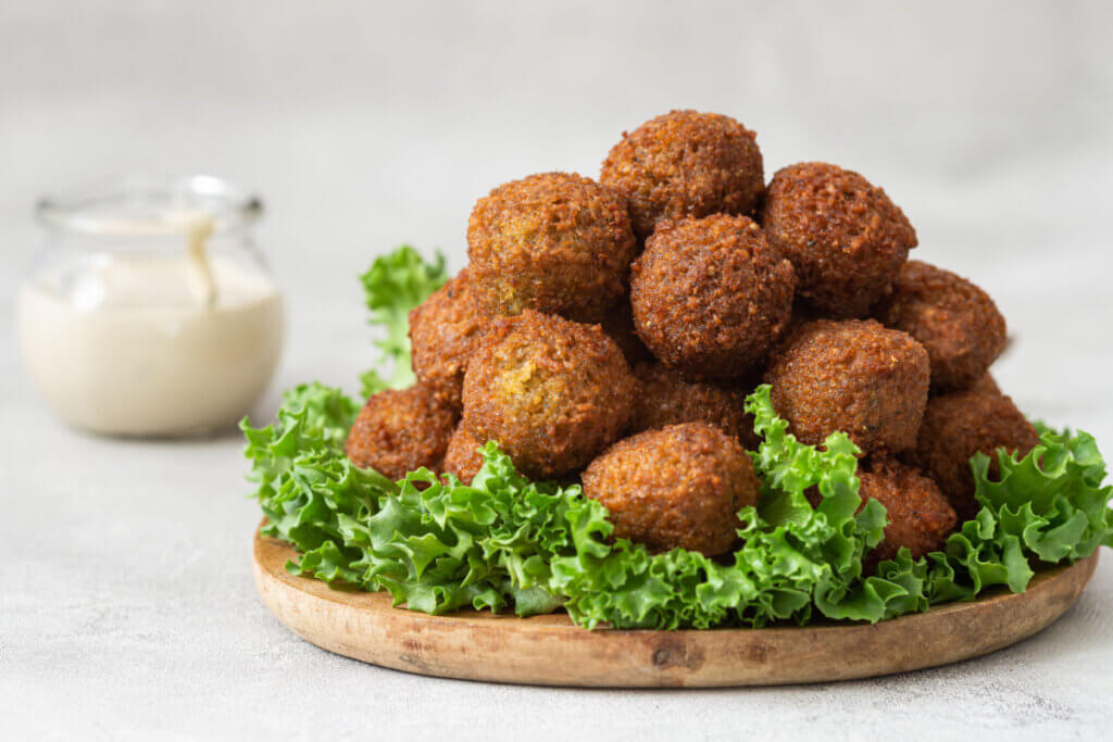 Bolinhos fritos empilhados em cima de tábua com folhas de alface