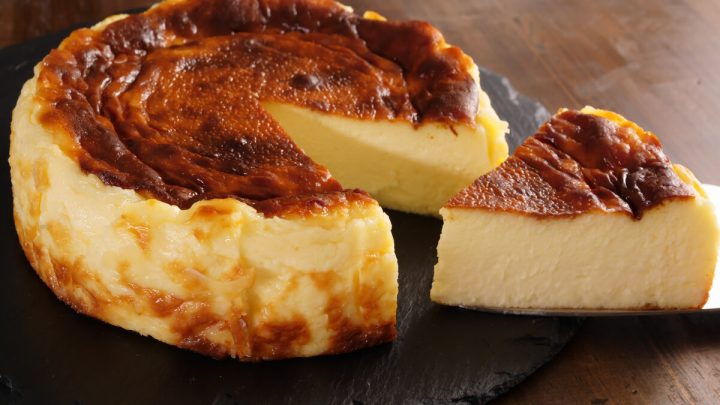 Cheesecake em cima de um recipiente preto com um pedaço cortado