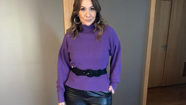 Maria Beltrão vestindo blusa rosa e calça preta posando para foto com a mão no bolso