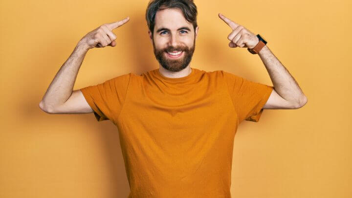 Homem sorrindo apontando para a cabeça