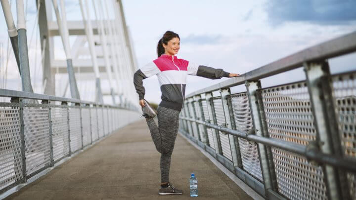 Mulher com roupa de frio fazendo exercícios em uma ponte