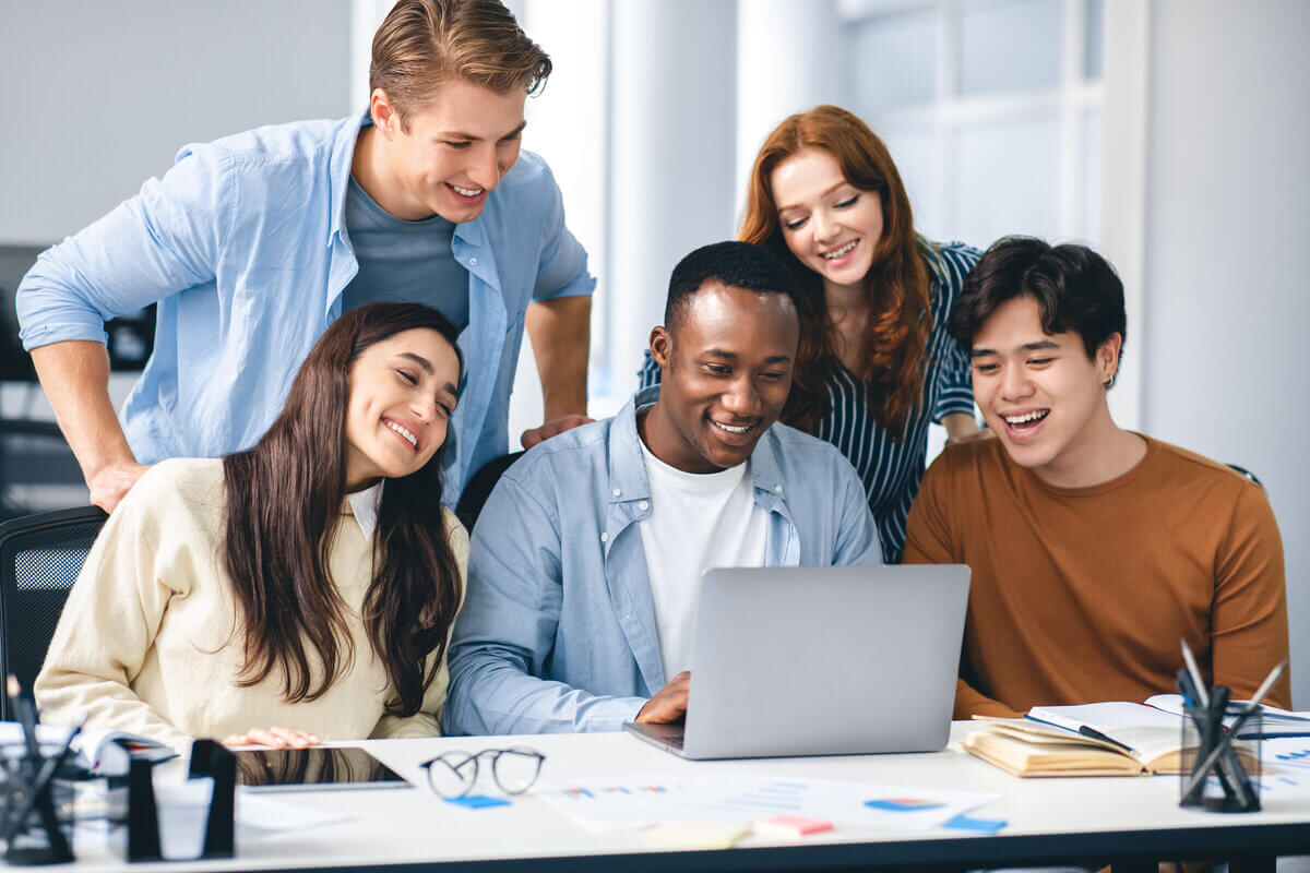 Estudantes reunidos em volta de um computador