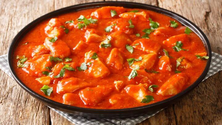 Panela preta com frango com molho de tomate polvilhado com coentro picado