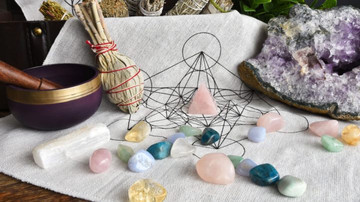 Pedras coloridas em cima de pano branco e outros itens de astrologia ao fundo