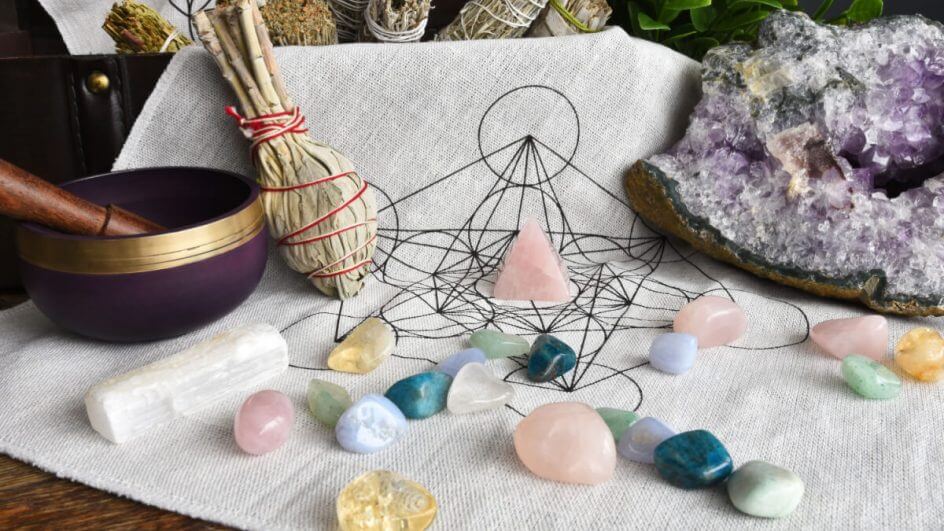 Pedras coloridas em cima de pano branco e outros itens de astrologia ao fundo