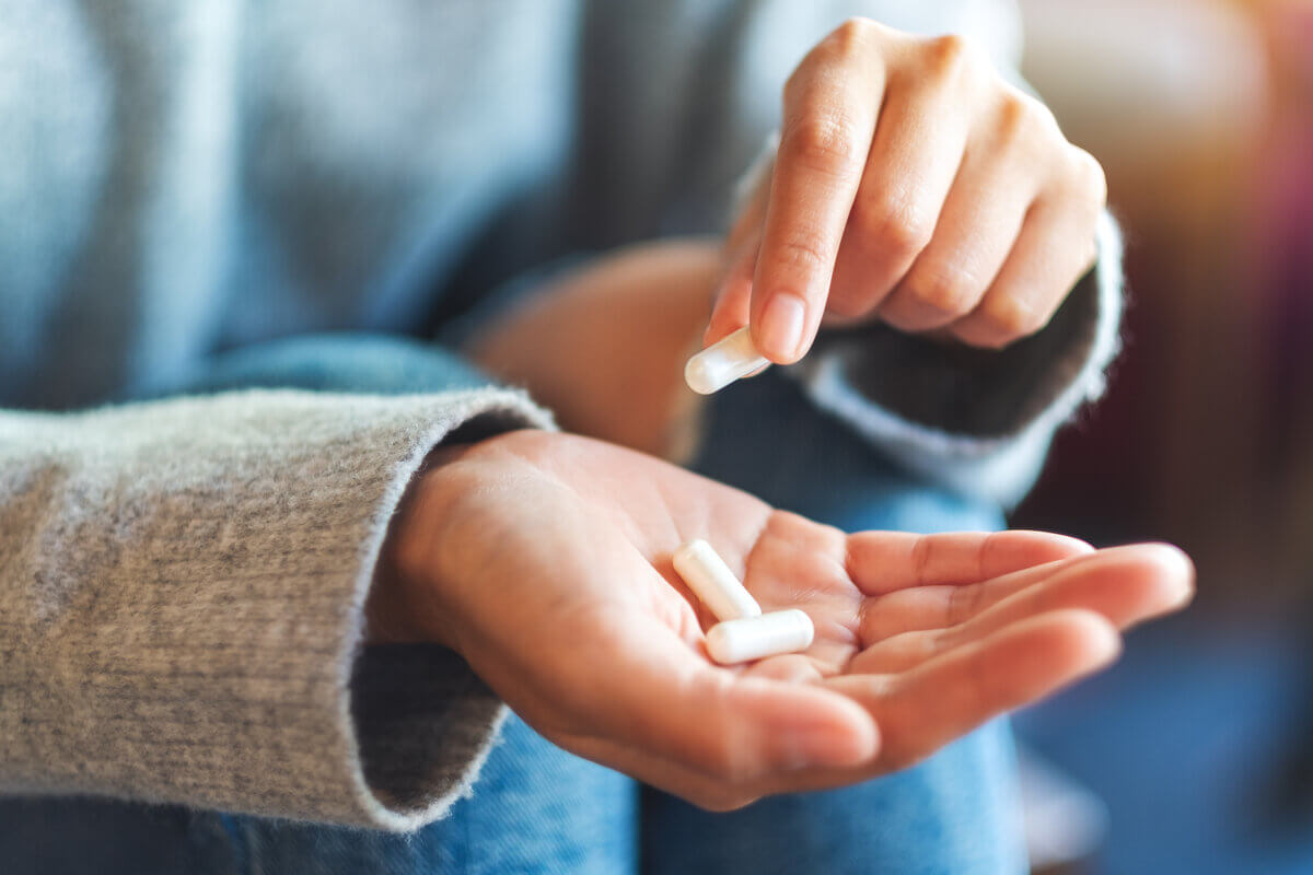 Mãos femininas segurando cápsulas de remédio
